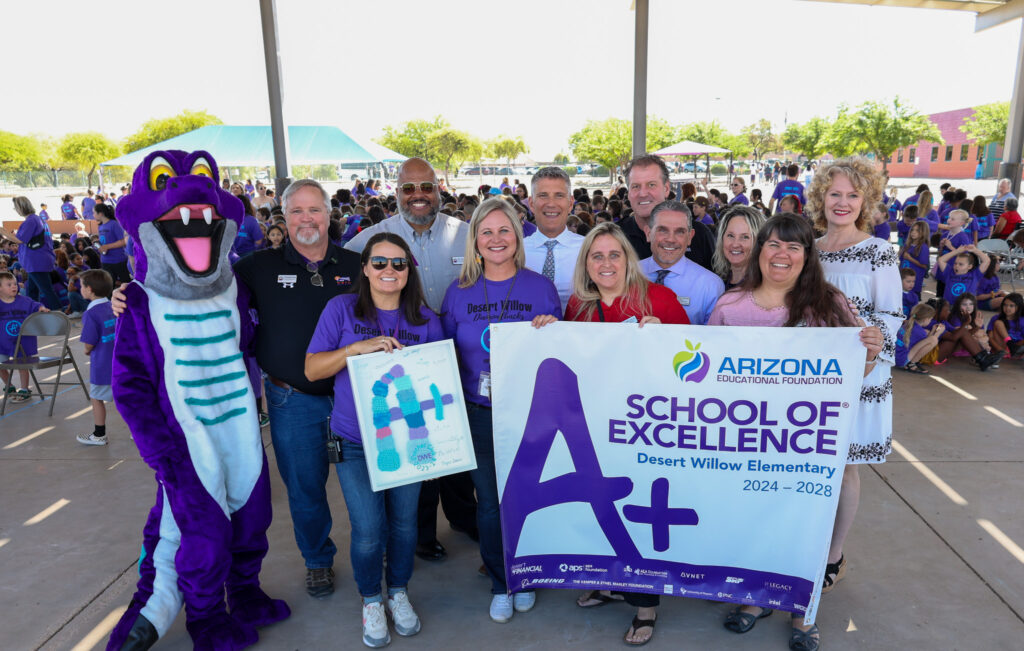 A group of people, including a purple mascot, hold an 